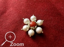 Agraffe aus Gold mit zentralen Korallencabouchon, mit Perlen umrandet